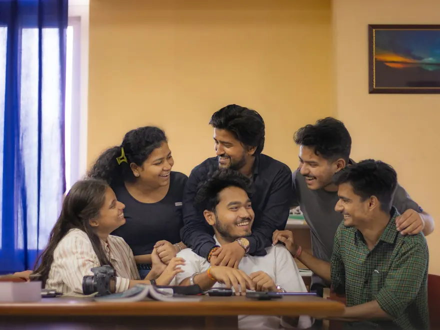 Group of young people laughing around a table